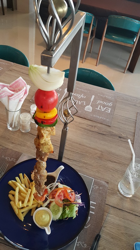 A Brochette with mixed meats and Prawns. A skewer on a metal frame.
